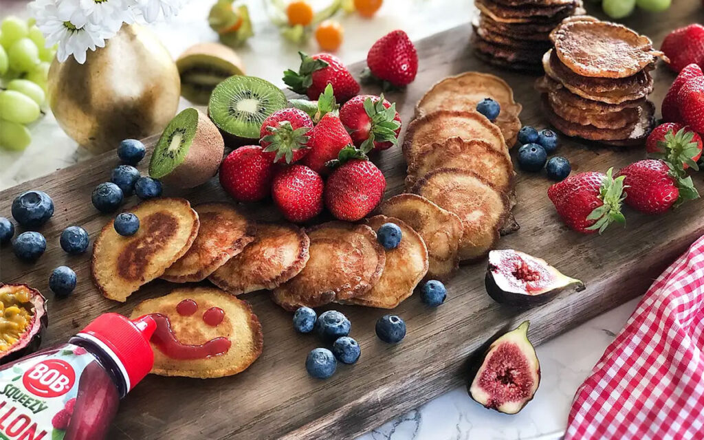 Pancake board med små pannkakor, blåbär, jordgubbar och fikon.