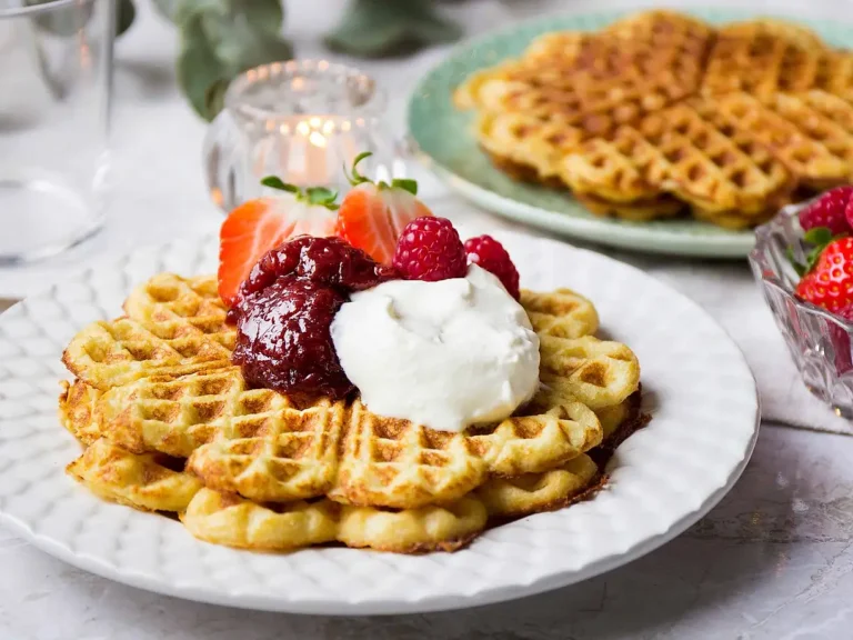 Tallrik med glutenfria våfflor med mandelmjöl toppade med jordgubbar, grädde och BOB jordgubbssylt.
